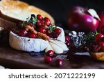 Small photo of Baked Camembert Brie cheese with a cranberry, honey, balsamic vinegar and nut relish and garnished with thyme. Served with toasted bread slices. Selective focus with blurred background and foreground.
