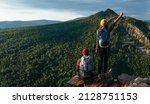 Small photo of A traveling couple in hiking gear in the mountains at sunset. Two tourists on the top of the mountain. A man and a woman in the mountains. Hiking in the mountains with backpacks. Two travelers