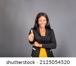 Small photo of Beautiful young dark haired black woman in eloquent clothing with a happy expression thump up for agreement sign with success business concept.