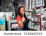 Positive dark skinned female sale girl posing proudly in cosmetic supermarket given a thumbs up