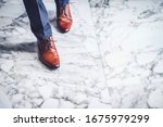 Small photo of Close-up of businessman feet in brown shoe on the marble floor, Get Ready to Moving Forward or take a Chance to Success.