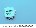 Job recruiting advertisement represented by 'WE ARE HIRING' texts at note. Image is used to represent the hiring position to be recruited and filled.