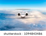 Front view of aircraft. Privat jet in flight. The passenger plane flies high above the clouds and blue sky. Luxury travel concept