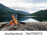Landscape of a campfire in a peaceful lake valley.