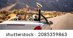 Small photo of Dreams come true! Two happy young girls driving cabrio car during vacation road trip in mountains, making memories and having fun together. Back view.Freedom concept. Happiness. Tourist.