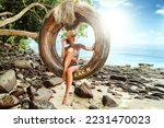 Woman relaxing on the tropical beach,, sitting on the boho swing. Travel concept. Dream island. Summer vibes. Thailand.