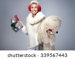 Smiling beautiful adult woman holding big teddy bear. Looking at camera. Studio shot. Winter style.