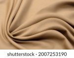 Abstract texture of natural beige or brown color fabric as concept background. Fabric texture of natural cotton or linen, silk or satin, wool or jersey textile material. Luxurious dark background.