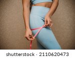 Small photo of Cropped view of slim woman measuring bdr with tape measure at home, close up. A European woman checks the result of a weight loss diet or liposuction indoors. Healthy lifestyle.