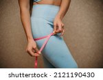 Small photo of Cropped view of slim woman measuring bdr with tape measure at home, close up. A European woman checks the result of a weight loss diet or liposuction indoors. Healthy lifestyle.