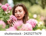 Small photo of Hydrangeas Happy woman in pink dress amid hydrangeas. Large pink hydrangea caps surround woman. Sunny outdoor setting. Showcasing happy woman amid hydrangea bloom.