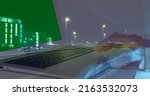Small photo of Image of hands of woman using laptop with green screen over sped up traffic in city at night. business and communication technology concept digitally generated image.