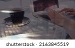 Small photo of Image of hands of woman with coffee using laptop, over sped up commuters walking in city. business and communication technology concept digitally generated image.