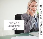 Small photo of Composite of we are here for you text and caucasian businesswoman talking on mobile phone in office. Copy space, samaritans awareness day, support, communication, technology and campaign concept.