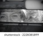 Beautiful eyes of a girl in the rearview mirror of a car. Black and white photo