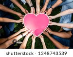 Group of people holding a pink heart icon