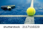 Small photo of Yellow ball on floor behind paddle net in blue court outdoors. Padel tennis is a racquet game. Professional sport concept