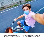 Small photo of one teenger alone in the middle of the street riding a vintage bike taking a selife and wearing surgical mask to prevent any type of virus or disease like coronavirus or covid-19 - happy people