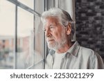 Pensive elderly mature senior man in eyeglasses looking in distance out of window, thinking of personal problems. Lost in thoughts elderly middle aged grandfather suffering from loneliness, copy space