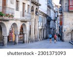 Small photo of PONTEVEDRA, SPAIN - AUGUST 6, 2022: Pilgrims walk through one of the streets of the city, next to the Camino de Santiago signpost.