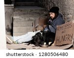 Small photo of Houseless man sitting with his dog on backstreet