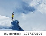 Adult man stand on the mountain top cliff with backpack and ski observe long alpine panorama to concur skiing