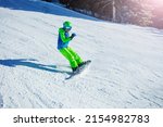 Action motion photo of a snowboarder boy on mountain ski slope with snow flying away from the snowboard