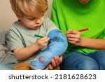 Small photo of Boy with brother draw broken hand plaster cast painting childish drawings using felt-tip pen