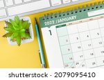 January 2022 desk calendar and diary with keyboard computer on yellow background.