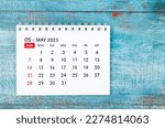 May 2023 Monthly desk calendar for 2023 year on old blue wooden background.