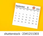September 2023 and wooden push pin on yellow background.