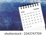 October 2023 Monthly desk calendar for 2023 year on old blue wooden background.