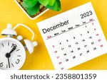 Small photo of December 2023 Monthly calendar for 2023 year with alarm clock on yellow background.