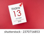 Calendar Friday the 13th October 2023 and push pin on red background.