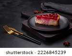 Homemade tasty cheesecake with jelly and raspberry berries on a black plate on a dark concrete background