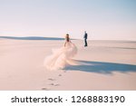 Small photo of silhouette woman runs meet man. Dress very long train fabric flies wind. tourist Art Photo back without face turned away rear view. UAE Dubai Desert white sand sunset concept happy Valentine's Day