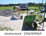 Small photo of Close up on concrete mixer, cement mortar mixing with construction wheel barrow on house construction site.