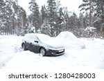 Black dirty car under the snow in forest. Heavy snowfall. Frozen car in snowdrift. winter problems to start engine