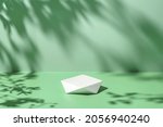 Abstract minimal nature scene - empty stage and polygonal podium on pastel mint green background and soft tree leaves shadows. Pedestal for cosmetic product and packaging mockups display presentation
