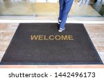 A welcome mat at the entrance of a cafe restaurant as a customer is seen entering through the front door.