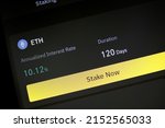 App with function to stake Ethereum for fixed interest rate and period. App allowing cryptocurrency hodlers to stake cryptos to earn rewards or interests on their holdings. Phone screen closeup view.