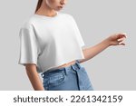 White crop top mockup on posing girl in jeans, isolated on background, front view. Free cut clothing template, empty oversized t-shirt, shirt for design, print, brand, advertising