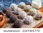 Assorted vegan sweets, Delicious Candy Balls with seeds, dried fruit, nuts, and cocoa powder, Healthy Candies with Chia, Sesame Seeds, Coconut and Truffles on wooden background
