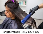 Small photo of Hairdresser using a hair straightened to straighten the hair. Hair stylist working on a woman's hair style at salon.