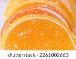 Small photo of Decorative Background of yellow and orange marmalade candy in the shape of citrus fruits wedges. Jelly sweet candies. Food Texture. Beautiful marmalade lemon wedges white background.