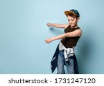 Small photo of Naughty boy in stylish cap jumping in place looking down under feet with roguish smile. Childhood, sly kid, troublemaker. Three quarter length portrait isolated on blue background. Copy space