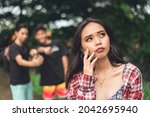 Small photo of A young asian woman is anxious about two guys identifying her in a viral scandalous post. A victim of cyberbullying and online bashing.