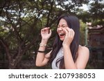 Small photo of A hysterical young woman laughs uncontrollably. Reacting to a very funny joke. Copyspace on the left. Outdoor scene.