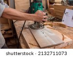 Small photo of Cutting a round shape from a thick slab of wood. Using a plunge wood router with a circle cutting jig. Making the head of a bar stool at a workshop.