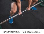 Small photo of An anonymous man doing sumo deadlifts. Using an alternate grip to pick up the barbell. Overhand on left hand and underhand on the right.